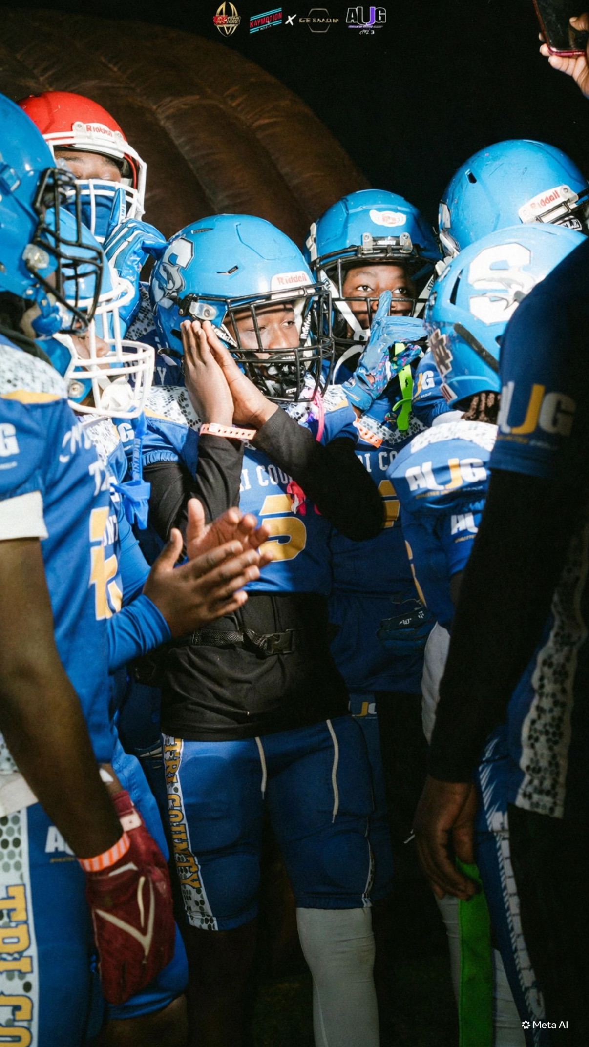 Youth football players at the line of scrimmage under the lights